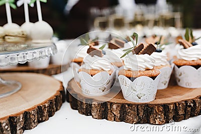 Vanilla cupcakes decorated with cream and berries on wooden place. Wedding cupcakes Stock Photo