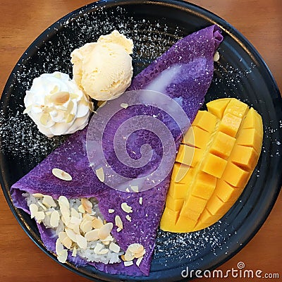 Vanilla ice-cream with mango, whip cream served with banana, chocolate filled crepe and natural honey Stock Photo