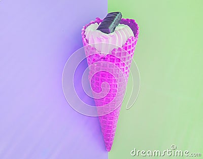 Vanilla pink ice cream cone with chocolate on a background of pastel shades of green and lilac, tinted shot Stock Photo