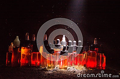 Vape concept. Smoke clouds and vape liquid bottles on dark background. Light effects. Stock Photo