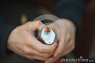 Vape. Electronic cigarette in male hands. Incandescent coils. Stock Photo