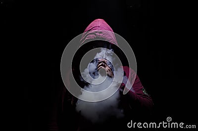 Vaping man holding a mod. A cloud of vapor. Black background. Vaping an electronic cigarette with a lot of smoke Stock Photo