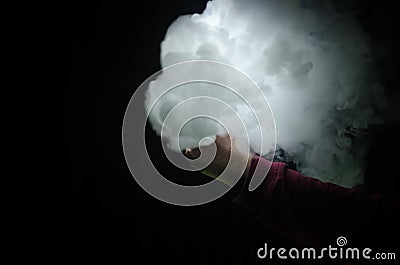 Vaping man holding a mod. A cloud of vapor. Black background. Vaping an electronic cigarette with a lot of smoke Stock Photo