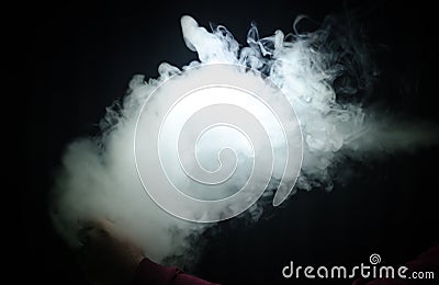 Vaping man holding a mod. A cloud of vapor. Black background. Vaping an electronic cigarette with a lot of smoke Stock Photo