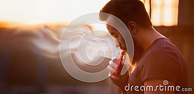 Vaping, young man with a beard, produces vapor sunset sky background, place for text Stock Photo
