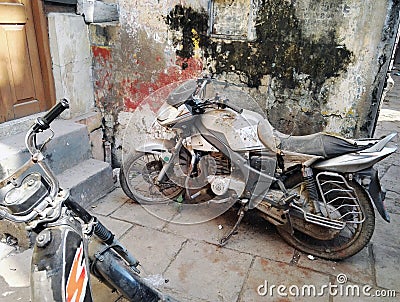 Varanasi, India: An old rusty damaged and flat tired Indian motor bike parked in a grungy corner of an alley Stock Photo