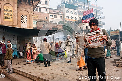 VARANASI, INDIA: Young man reads a newspaper in the crowd of hindu people at the morning Editorial Stock Photo