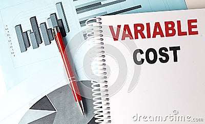 VARIABLE COST text on a notebook with pen on a chart background Stock Photo