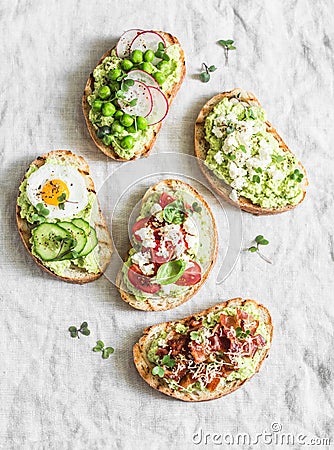 Variation avocado sandwich - with crispy bacon, quail egg, tomatoes, goat cheese, green peas, radish, cucumber. Healthy snack. On Stock Photo