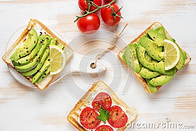 Variation of healthy breakfast toasts with avocado and cherry tomatoes on white wooden background. Food concept Stock Photo