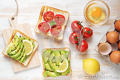 Variation of healthy breakfast toasts with avocado and cherry tomatoes on white wooden background. Food concept Stock Photo