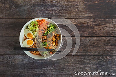 Variation of ramen homemade soup with noodles, marinated tofu, chopped carrots, onions, lettuce and broccoli in a bowl lying on a Stock Photo