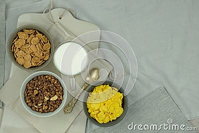 Variety of breakfast cereals, muesli and milk in bowls on a light wooden background. Fast food. Top view. Space for text Stock Photo