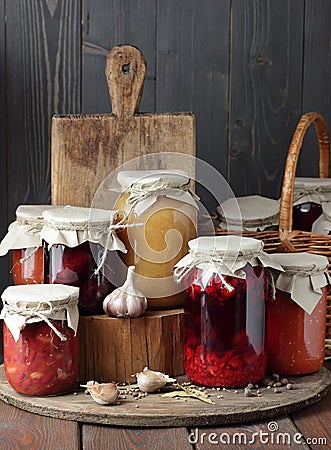 Variety of canned vegetable food: conserved beetroot, tomato paste, preserved bean, jam, pickles on wooden rustic background Stock Photo