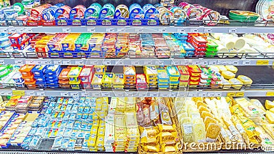 a variety of cheeses in the refrigerated display case In a large supermarket Editorial Stock Photo