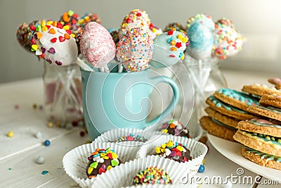 Variety of decorated candies, cake pops and cookies on white desk Stock Photo