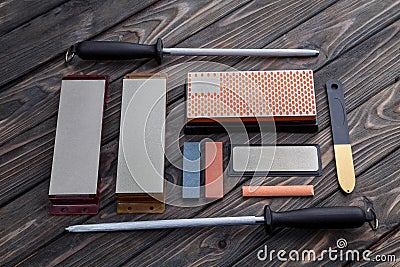 A variety of knife sharpeners. Sharpening stones and devices on a wooden background. Grinding stones Stock Photo