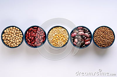 A variety of legumes. Lentils, chickpeas, peas and beans in blue bowls on a white background. Top view Stock Photo