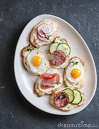 Variety of mini sandwiches with cream cheese, vegetables, quail eggs and salami. Sandwiches with cheese, cucumber, radish, tomatoe Stock Photo