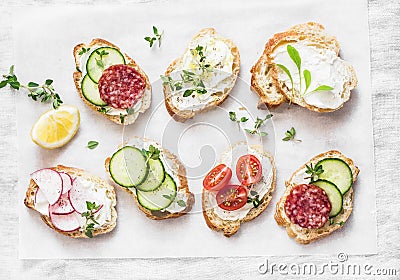 Variety of mini sandwiches with cream cheese, vegetables and salami. Sandwiches with cheese, cucumber, radish, tomatoes, salami, t Stock Photo