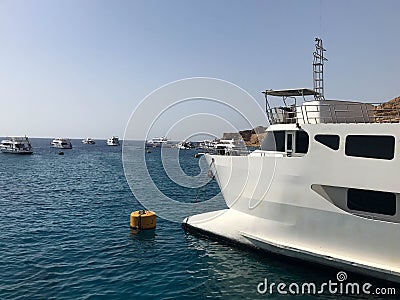 A variety of motor and sailing ships, boats, cruise liners stand on a dock in the port against the background of the blue sea and Stock Photo