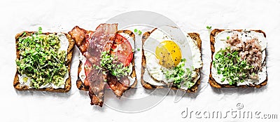 Variety of sandwiches for breakfast, snack, appetizers - avocado puree, fried egg, tomatoes, bacon, cheese, smoked mackerel Stock Photo