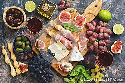 A variety of snacks, prosciutto,grapes, wine, cheese with mold, figs, basil, olives on a rustic background. Top view,flat lay Stock Photo