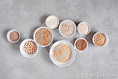 Various cereals and beans in white plates on gray textured table Stock Photo