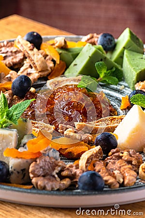 various cheeses on a plate with nuts and confitures. Stock Photo