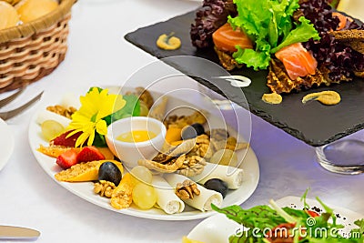 Various cold snacks on the table in the restaurant: cheese, salmon, vegetables and more Stock Photo