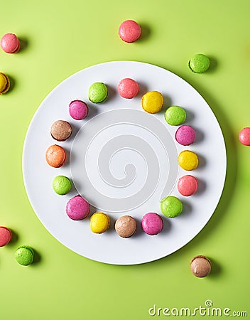 Various colored mini macarons on white plate and light green background, top view Stock Photo