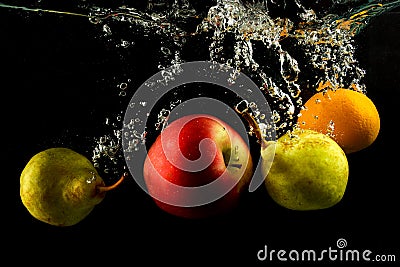 Various fruits pear, orange and apple splash of water on black Stock Photo