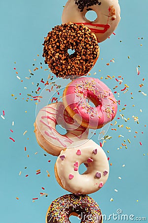 Various decorated doughnuts in motion falling on blue background Stock Photo