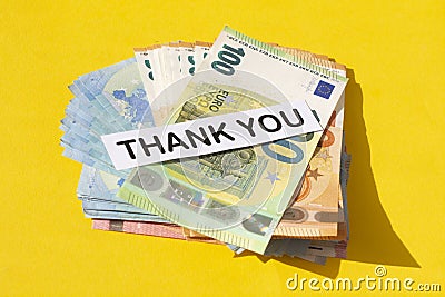 Various denominations of euro banknotes and the words thank you isolated on yellow background Stock Photo