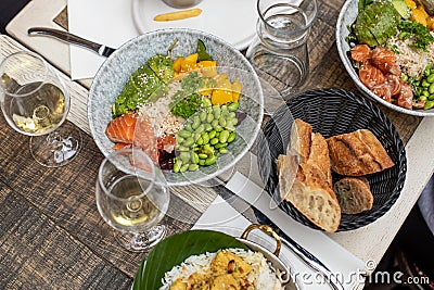 Various dishes and glasses with wine lying on table of French restaurant. Salads, bread arranged on plates on repast. Stock Photo