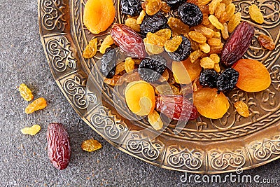 Various dried fruits on toreutic plate over stone background Stock Photo