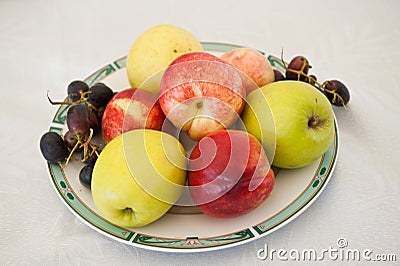 Various fruits on plate. Fresh and colored apples, grapes and nectarines on table Stock Photo