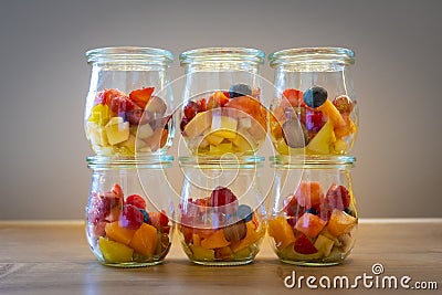 Various glasses containing vitamins with cut pieces of fruit on a wooden plate Stock Photo