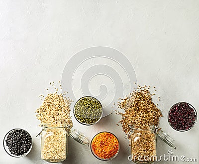 Various grains and beans, including rice, buckweat, lentils, Mung beans in glass jars on the table in the kitchen Stock Photo