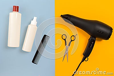 Various hair styling devices on the color blue, yellow paper background, top view Stock Photo