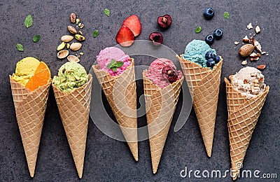 Various of ice cream flavor in cones blueberry ,strawberry ,pistachio ,almond ,orange and cherry setup on dark stone background . Stock Photo