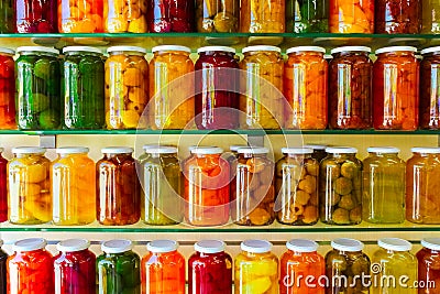 Various jars with Home Canning Fruits and Vegetables jam on glass shelves Stock Photo