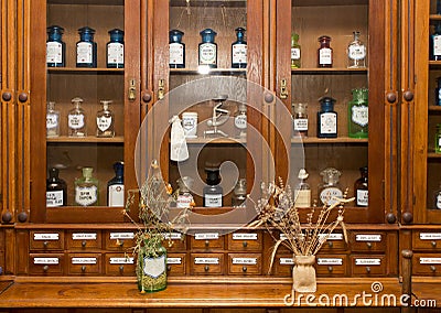 Different vials of medications are stored behind the glass in the store window in an old pharmacy Editorial Stock Photo