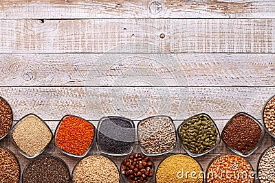 Various seeds and grains in bowls on old wooden table - with cop Stock Photo