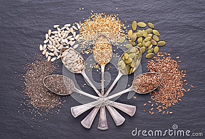 Various seeds - sesame, flax seed, sunflower seeds, pumpkin seed, chia in spoons on black background. Top view Stock Photo