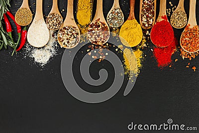 Spices in wooden spoons on black background. Stock Photo