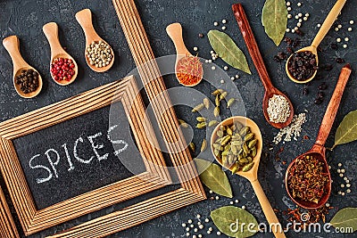 Various spices in wooden spoons on dark stone table. Stock Photo