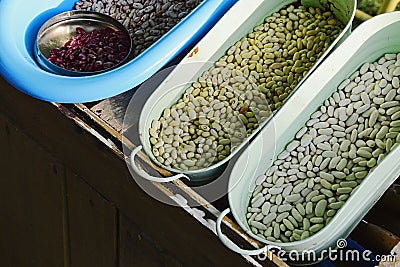 Various types of beans Phaseolus Vulgaris sorted in steel and plastic bowls and cans in wooden crate Stock Photo