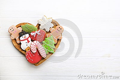 Various types of Christmas decorative gingerbread cookies on wooden heart shaped plate on white table top view, text space Stock Photo