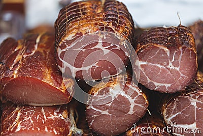Various types of ham at a market. Slices of different smoked ham displayed on the market stand Stock Photo